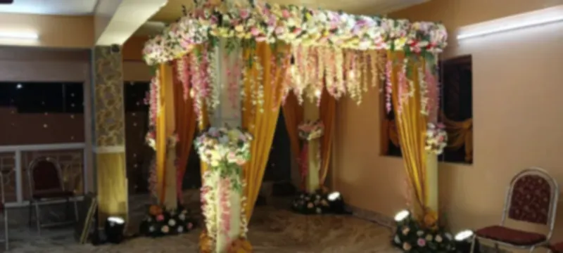Four-pillar mandap dressed in gold drape and fresh flower canopy