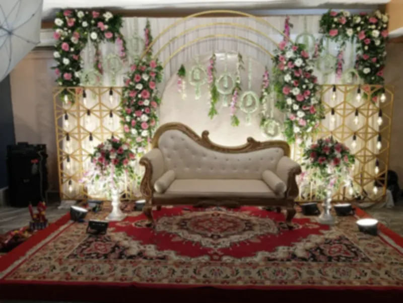 A gold trellis reception stage with a settee, flowers and a patterned carpet