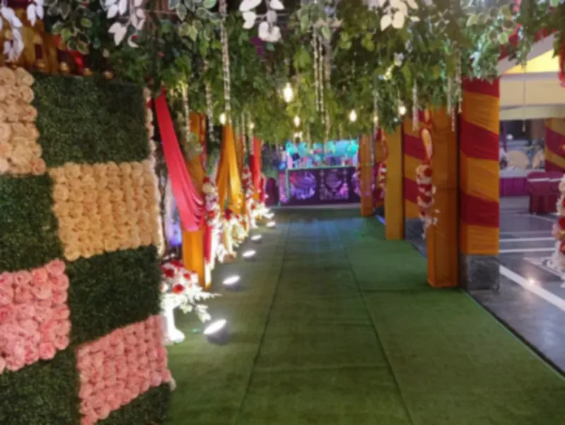 Green carpet walkway with flower walls leading to a lit counter