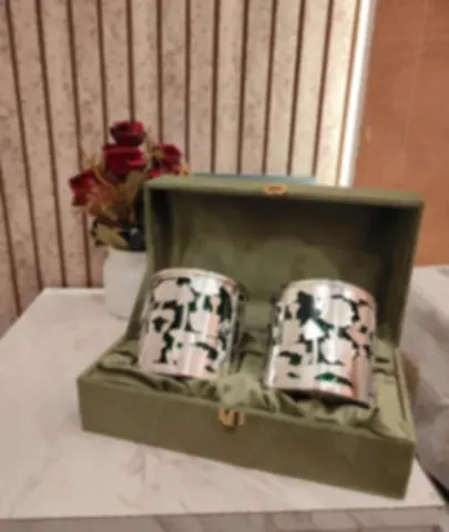 Two silver-plated barni jars in a green velvet presentation box