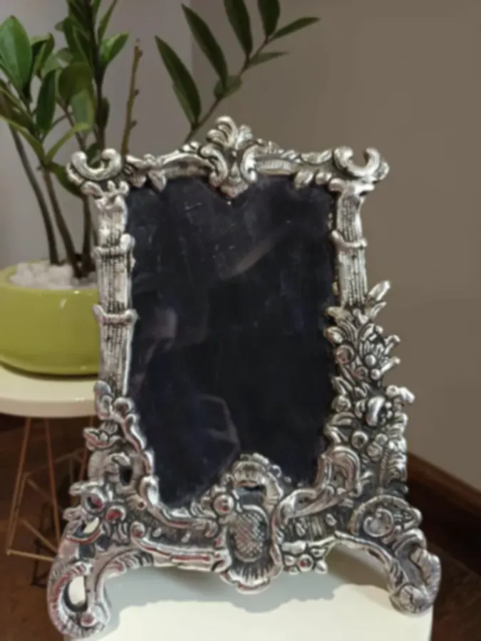 A standing mirror in an ornate baroque-style silver-plated frame