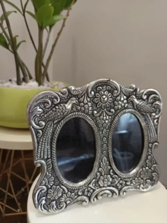 A twin silver-plated frame with two oval windows and bird motifs