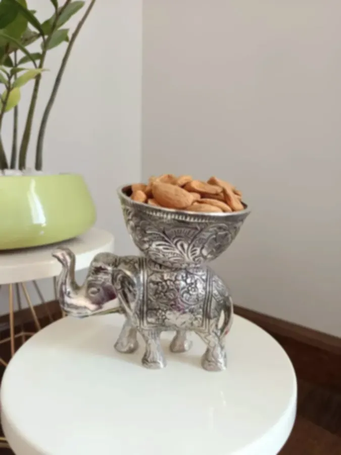 A small silver-plated elephant carrying a worked bowl filled with almonds