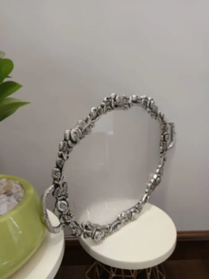 An oval mirror tray with a silver-plated floral rim
