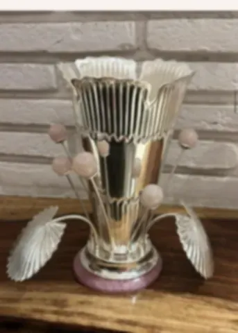 A fluted silver vase decorated with strings of rose quartz beads