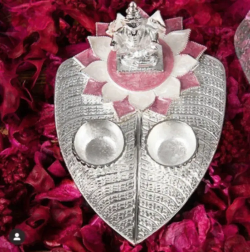 A paan-leaf shaped silver puja tray with a Ganesh figure and pink enamel lotus