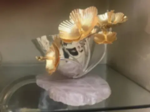 Gold-plated flowers rising from a silver bowl mounted on a rose quartz slab