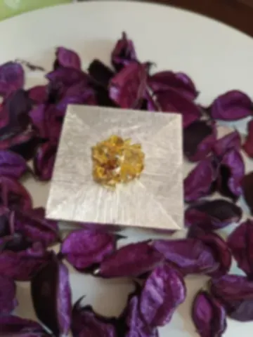 A square silver trinket box with a cluster of gold flowers on the lid