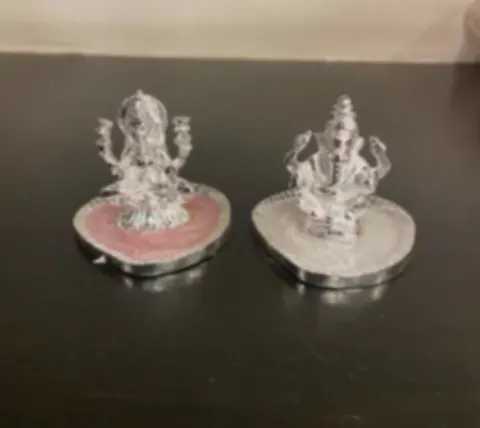 Silver-plated Lakshmi and Ganesh idols on rose quartz and white stone bases