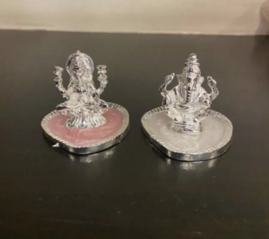 Small silver-plated Lakshmi and Ganesh idols seated on rose quartz and white stone bases