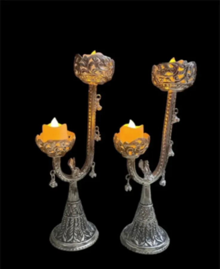 A pair of tall silver-plated candle stands with lotus cups and hanging drops