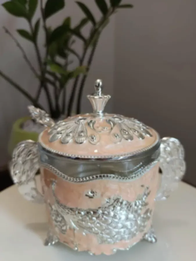 A casket of pink pearl resin wrapped in silver peacock relief work