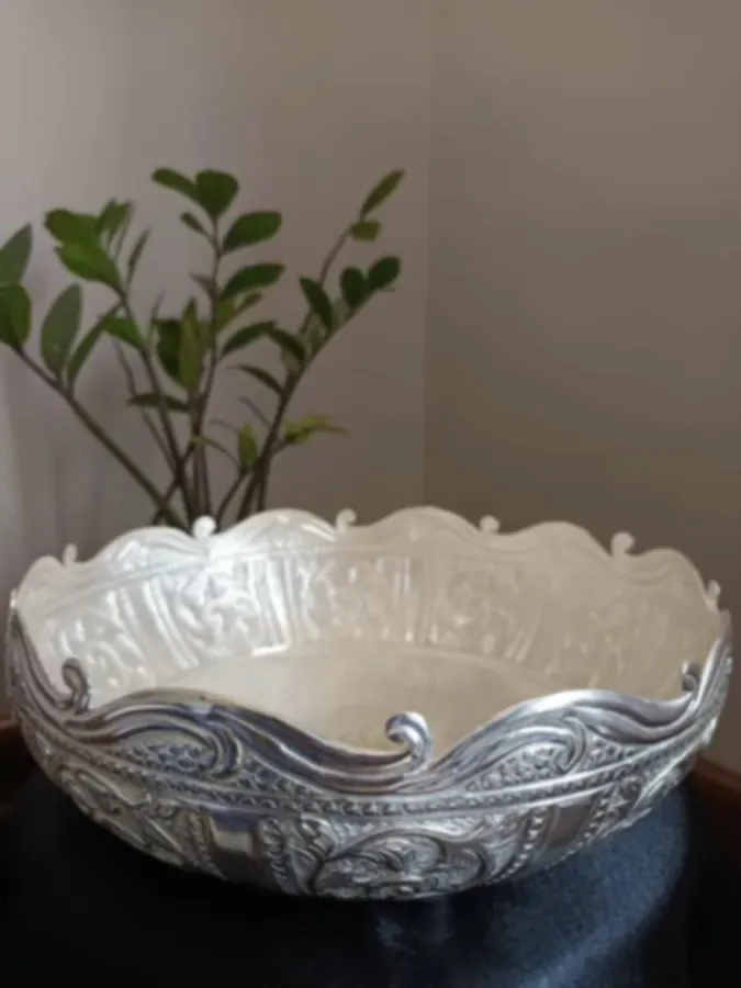 A pearl-white bowl with carved silver-plated rim and base