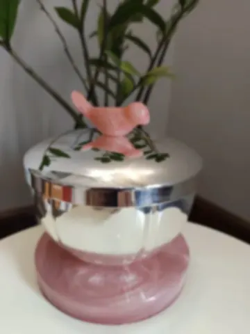 A mirror-polished silver casket with a carved rose quartz bird on its lid
