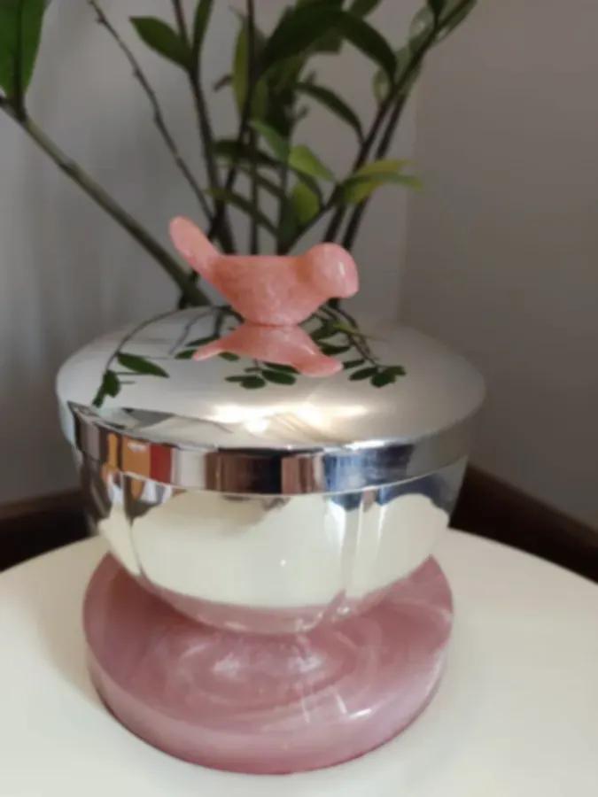 A mirror-polished silver casket on a rose quartz base, its lid topped with a carved quartz bird