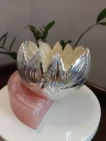 A bowl of overlapping silver leaves standing on a crescent of rose quartz