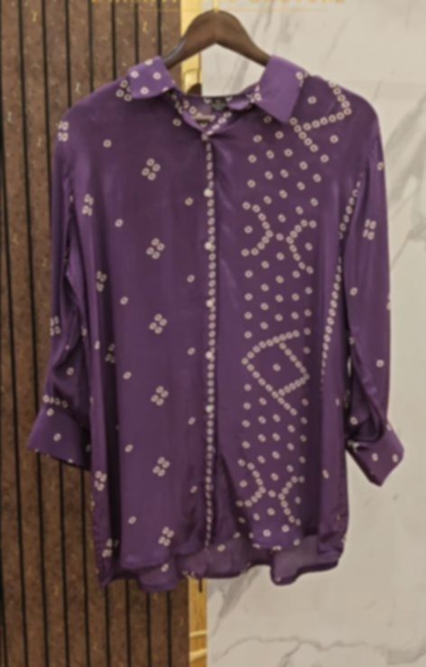 A purple bandhani shirt on a hanger, its small white circles falling in curved lines across the body and sleeves.