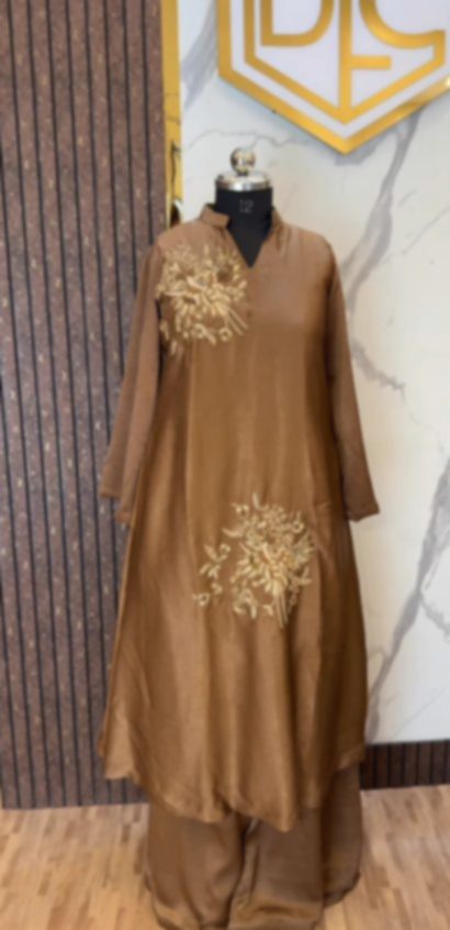 A caramel brown kurta and matching trousers on a mannequin, gold thread flowers worked at the shoulder and at the hem.