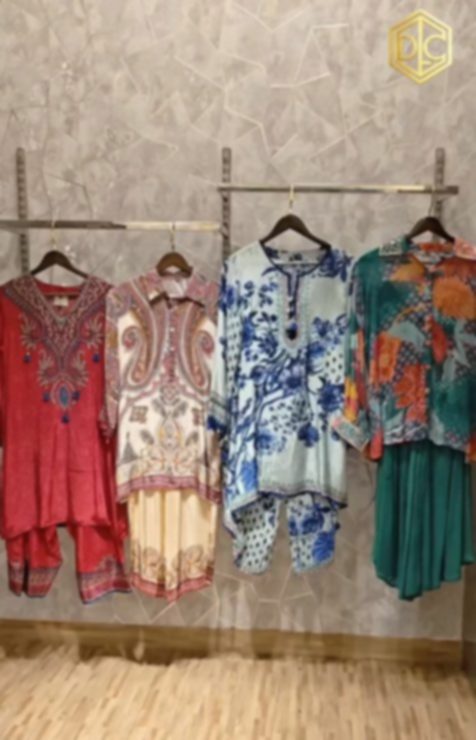 Four printed sets on a rail above a wooden floor, in red, cream, cornflower blue and deep teal.