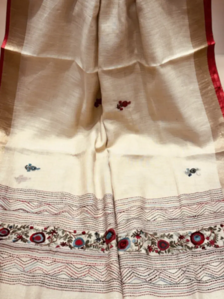 A length of pale tussar hanging, with a band of kantha running-stitch and small mirror-work flowers across the lower end.