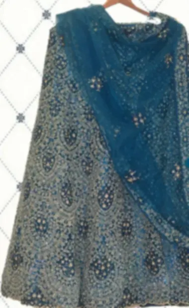 Peacock blue lehenga covered in silver stone work, with a matching sheer dupatta.