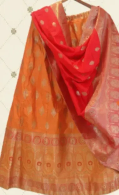 Orange woven lehenga with gold motifs and a bright red contrast dupatta.