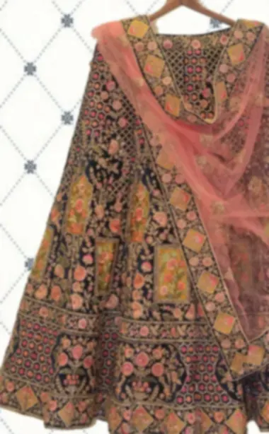Dark plum lehenga with dense multicoloured floral embroidery and a blush net dupatta.