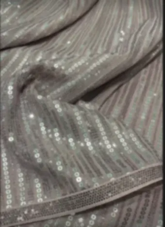 Rows of sequins stitched in stripes across a soft grey drape.