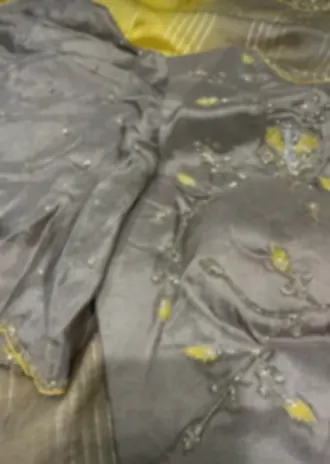 An unstitched grey suit piece with fine thread embroidery and a yellow contrast panel.
