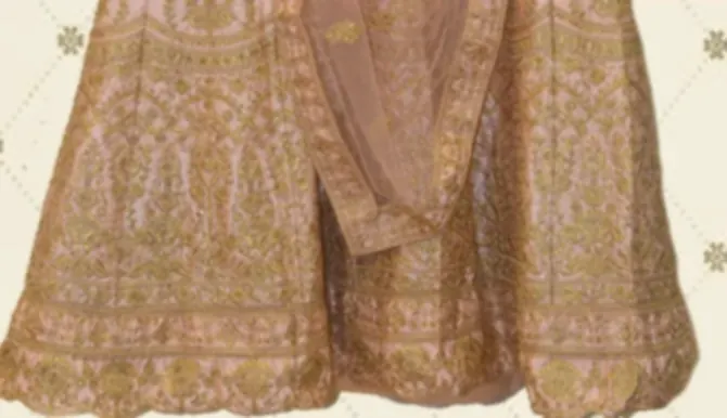 The hem of a blush pink bridal lehenga, the whole skirt worked in dense gold zari with a scalloped edge.