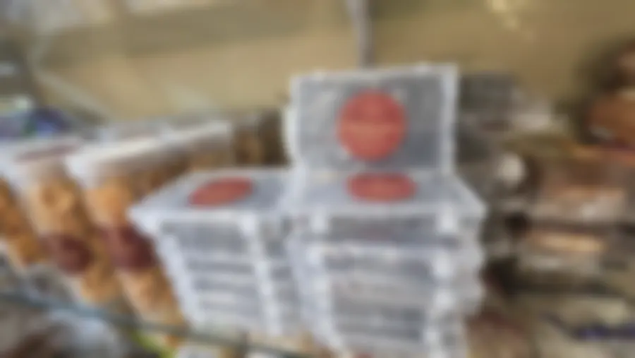 Stacked boxes of honey dry-fruit cake with maroon Copperpot labels beside jars of murukku, the kind of shelf a bulk order empties
