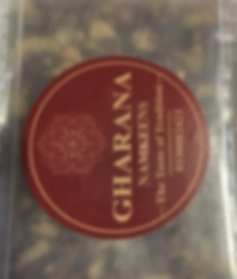 A clear box of dense dry-fruit cake, the maroon Copperpot Namkeen House label on its lid, held up to the light