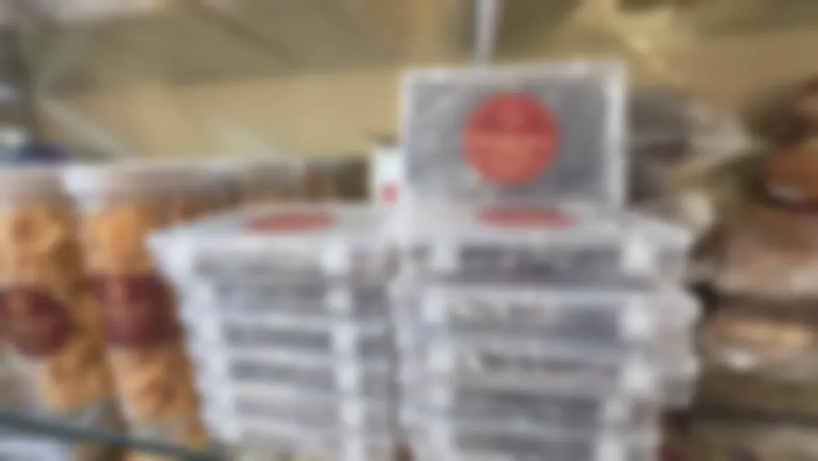 Stacked clear boxes of honey dry-fruit cake beside jars of murukku, every one carrying the maroon and gold Copperpot label
