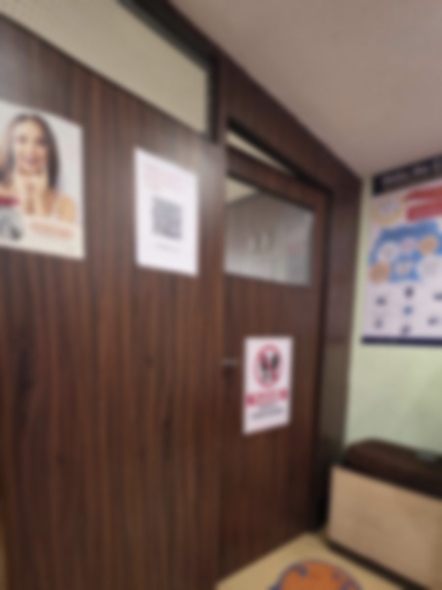 The waiting area at Quillfield Dental: the door through to the treatment room, a notice asking visitors to remove their shoes, and oral health posters on the wall.