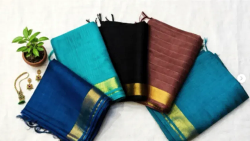 Four blended tussar sarees in teal, black, brown and blue, folded to show their gold borders.