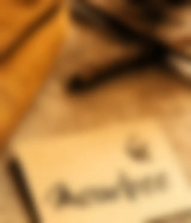 The Ranghaat Handlooms mark and name, handwritten in ink on a kraft card, resting on folded ochre khadi and woven jute.