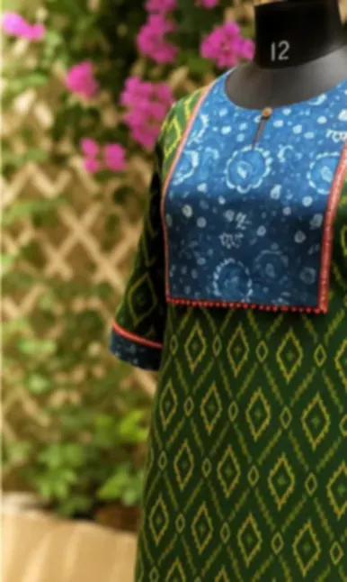 A green cotton kurti with a Dabu printed indigo yoke, on a mannequin outdoors.