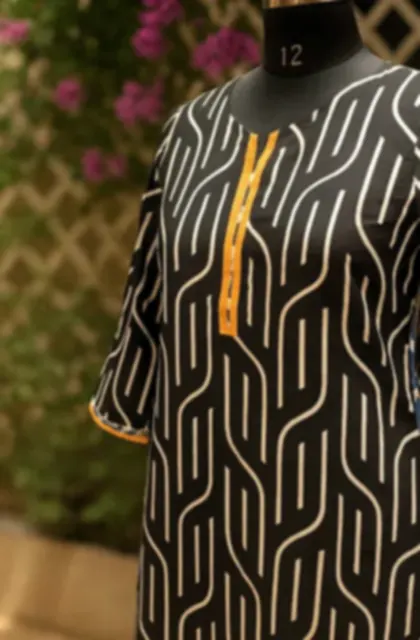 An olive cotton kurti printed with a flowing geometric pattern, on a mannequin outdoors.
