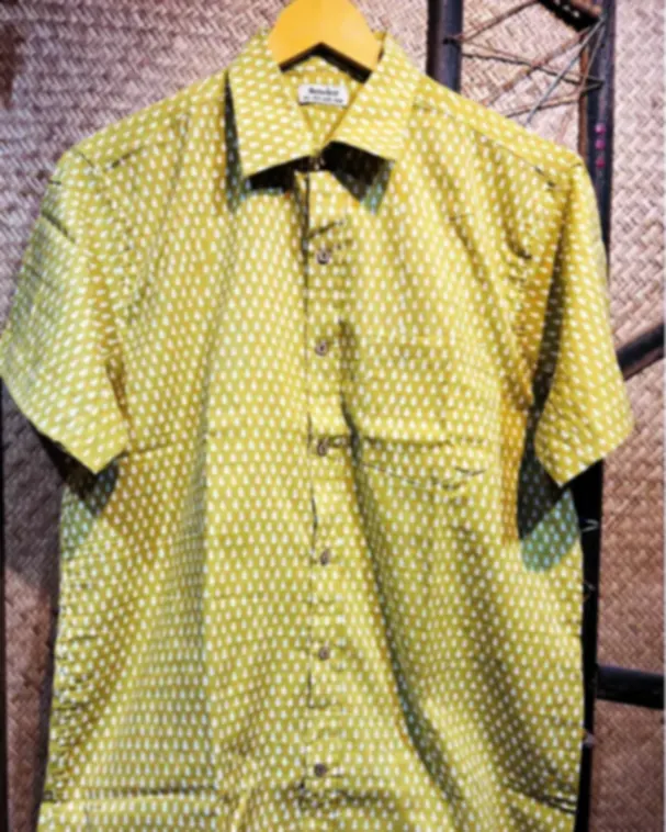 An olive green Dabu printed pure cotton shirt with a small repeating motif, on a hanger.