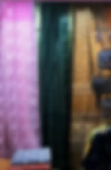 Pink, teal and printed drapes hanging side by side above a shelf of folded cloth.