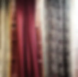Sarees in maroon, cream and printed cotton hanging together on a rail inside the shop.
