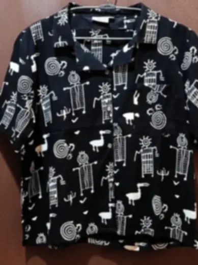 A navy shirt printed with graphic folk-inspired figures and symbols on skin-friendly cotton.
