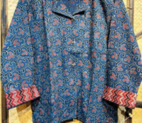 A deep indigo cotton shirt with classic Ajrakh detailing and a contrast printed cuff, on a hanger.